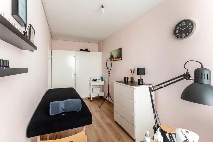 De salon met behandelbank, lamp en witte kasten
